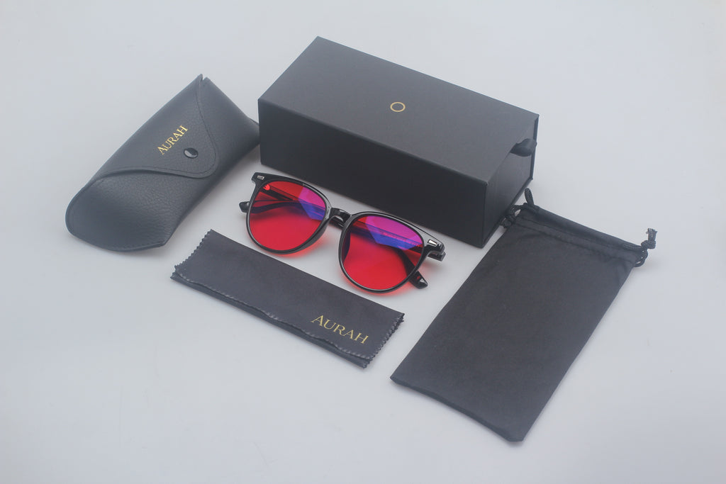 Red sunglasses with black frames in a branded case on a light gray background